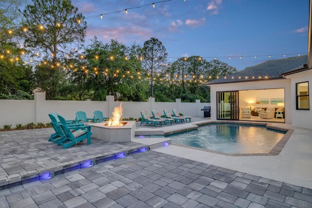 view of swimming pool featuring a fire pit, a patio area, fence, and grilling area