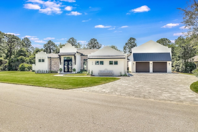 modern home featuring french doors, stucco siding, a front yard, and decorative driveway