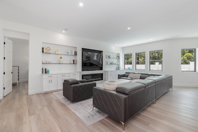 living area with light wood finished floors, recessed lighting, baseboards, and a glass covered fireplace