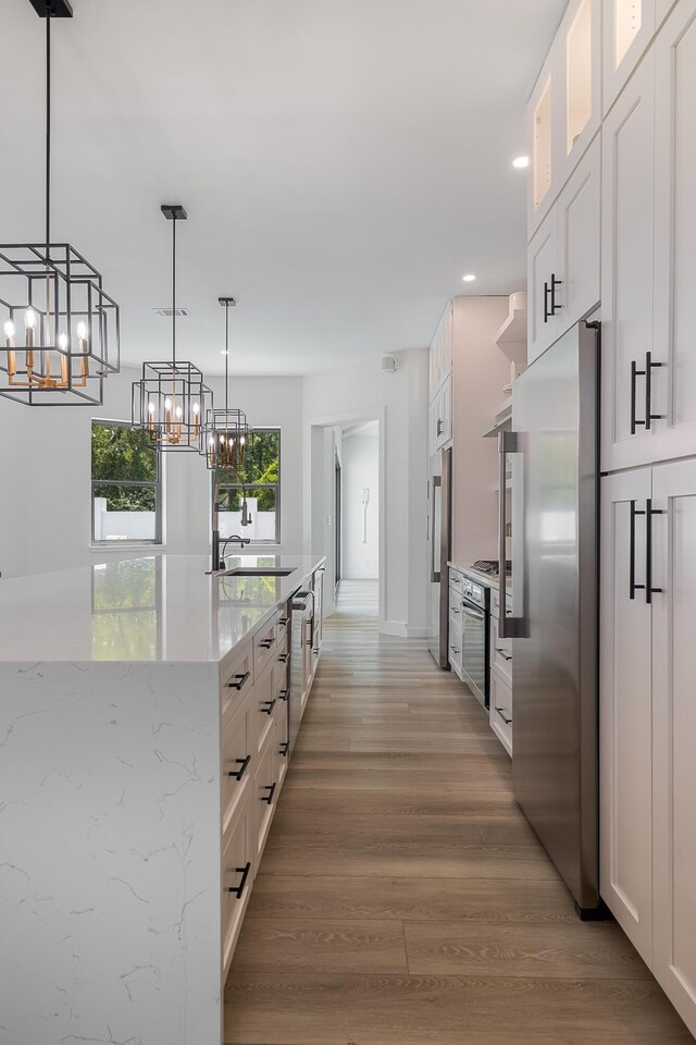 kitchen featuring stainless steel appliances, a chandelier, white cabinets, recessed lighting, and glass insert cabinets