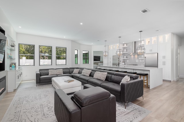 living area featuring light wood finished floors, recessed lighting, a chandelier, and baseboards