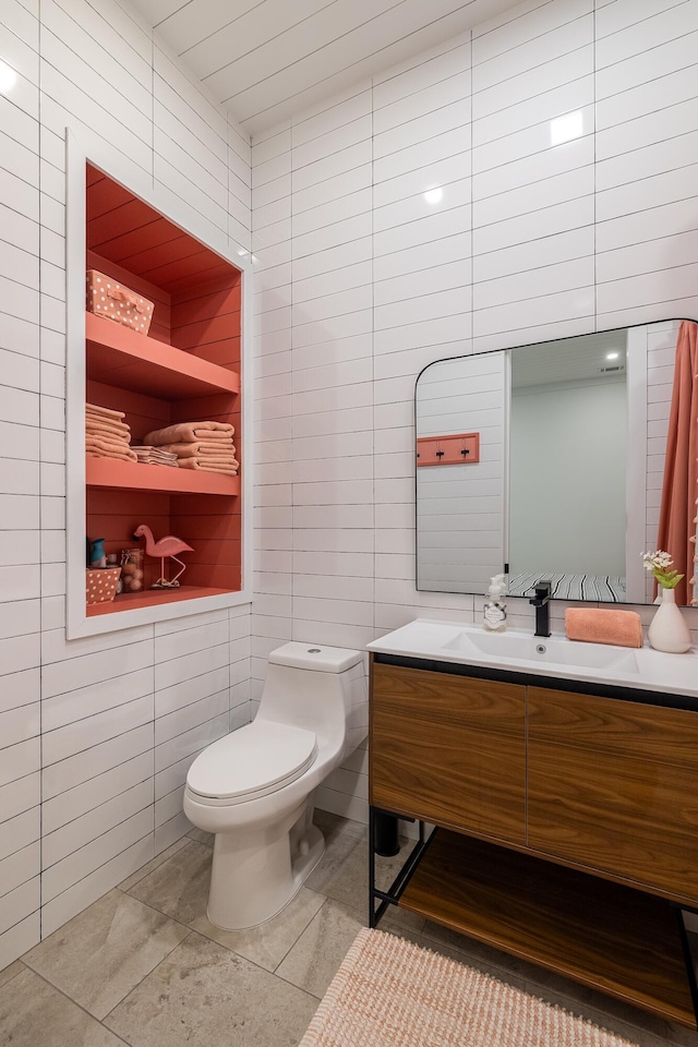 bathroom with tile walls, toilet, vanity, and tile patterned floors