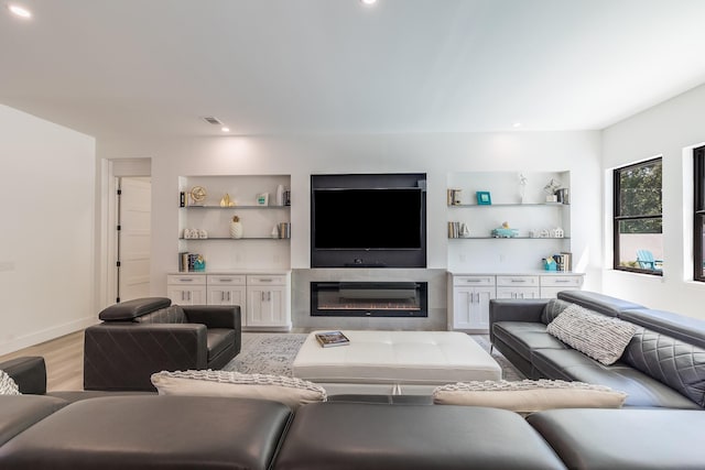 living room with light wood-style floors, a glass covered fireplace, recessed lighting, and baseboards