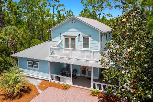view of front of house featuring french doors, a balcony, a porch, and metal roof