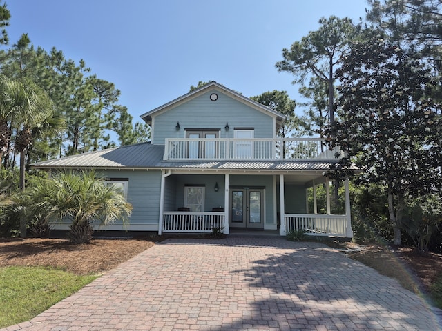view of front of home with covered porch, french doors, metal roof, and a balcony