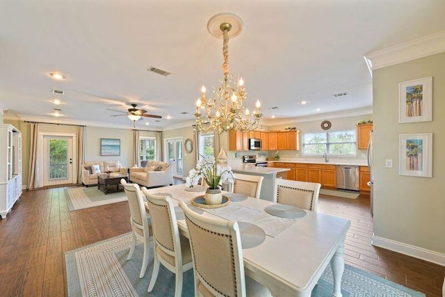 dining space featuring ornamental molding, healthy amount of natural light, a ceiling fan, baseboards, and a chandelier