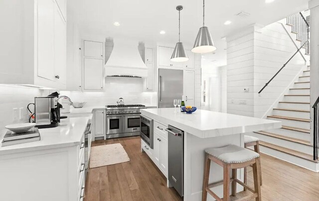 17 Compass Point Way, Watersound, FL 32461 - kitchen featuring custom range hood, premium appliances, wood finished floors, a breakfast bar, and recessed lighting