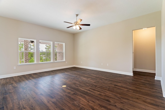 spare room featuring a ceiling fan, dark wood-style floors, and baseboards