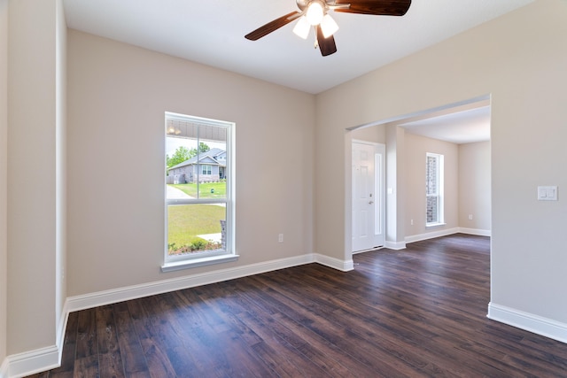 spare room with dark wood-type flooring, ceiling fan, and baseboards