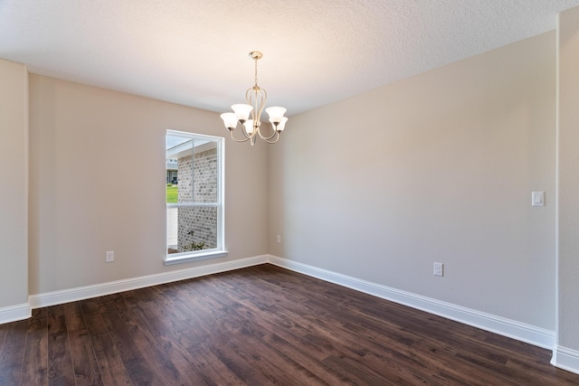 unfurnished room with a chandelier, dark wood finished floors, and baseboards