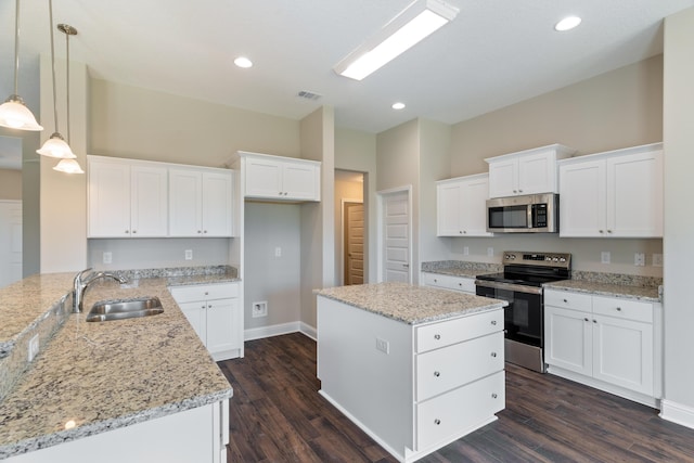 kitchen featuring appliances with stainless steel finishes, a sink, dark wood-type flooring, light stone countertops, and white cabinetry