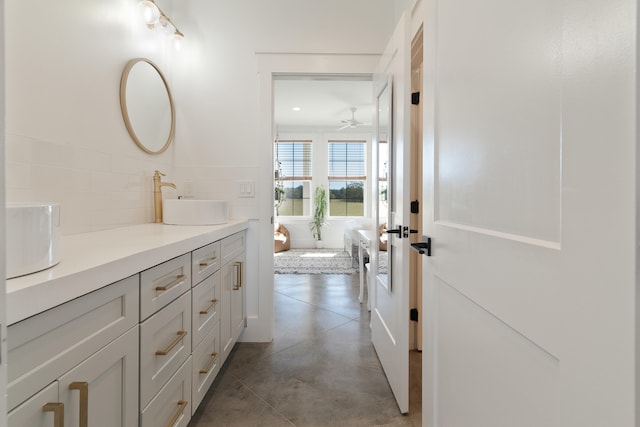full bathroom with double vanity, a bathtub, a ceiling fan, concrete flooring, and tasteful backsplash