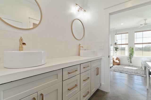 bathroom featuring a ceiling fan, double vanity, finished concrete floors, and tile walls
