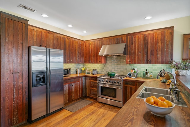 25 17th St, Apalachiacola, FL 32320 - kitchen with stainless steel appliances, extractor fan, a sink, tasteful backsplash, and light wood finished floors