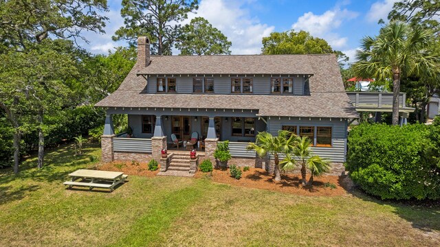 25 17th St, Apalachiacola, FL 32320 - view of front facade with a porch, a front yard, a chimney, and roof with shingles