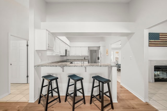 149 Kel Wen Cir, Destin, FL 32541 - kitchen featuring appliances with stainless steel finishes, a peninsula, light stone countertops, white cabinets, and a kitchen breakfast bar