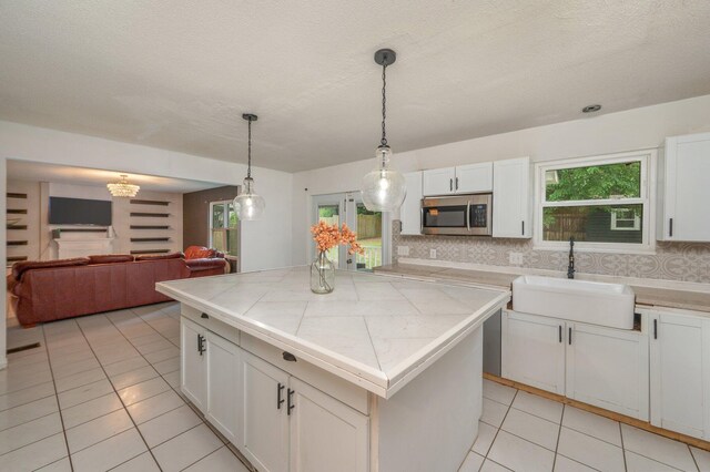 124 Palmetto Dr, Crestview, FL 32539 - kitchen featuring a sink, stainless steel microwave, tile countertops, light tile patterned floors, and backsplash