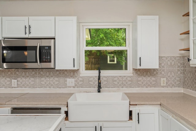 124 Palmetto Dr, Crestview, FL 32539 - kitchen featuring stainless steel microwave, a sink, white cabinets, and light countertops
