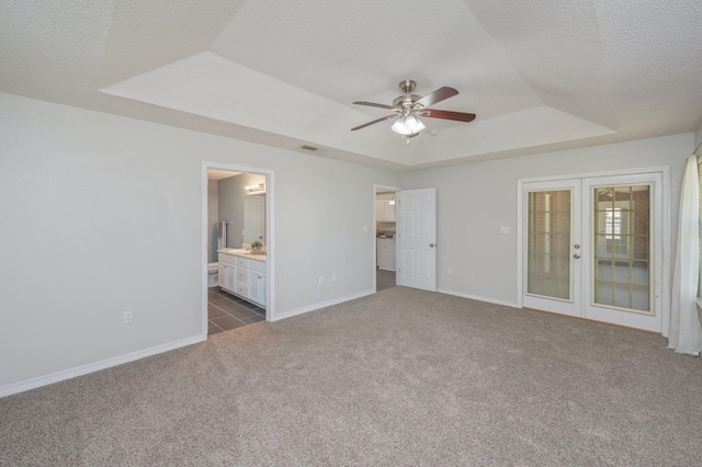 unfurnished bedroom featuring a raised ceiling, dark colored carpet, french doors, baseboards, and a textured ceiling