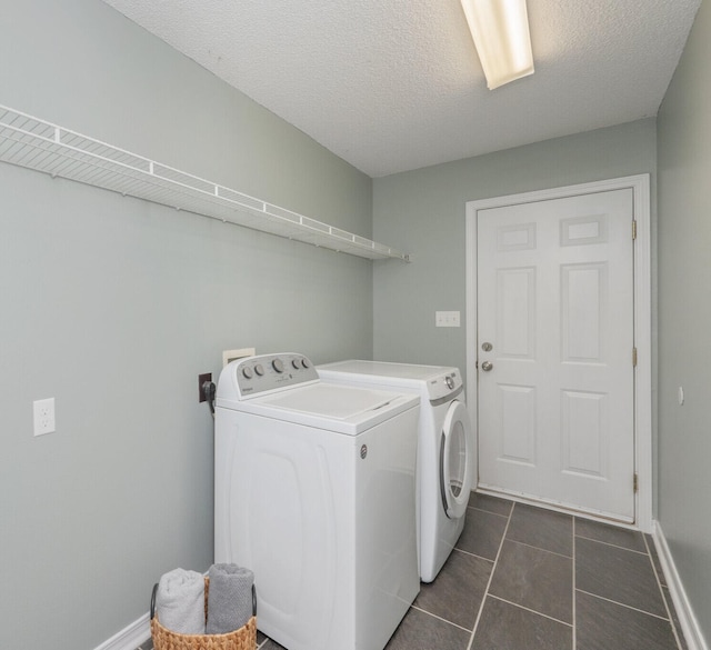 washroom featuring separate washer and dryer, baseboards, dark tile patterned floors, and a textured ceiling