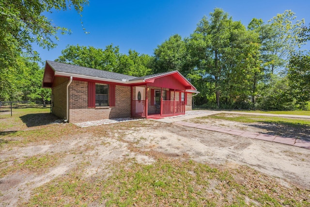 205 Florence Dr, Defuniak Springs, FL 32433 - view of front of house featuring brick siding, fence, and covered porch