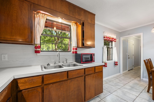 205 Florence Dr, Defuniak Springs, FL 32433 - kitchen featuring a sink, light countertops, brown cabinets, crown molding, and tasteful backsplash