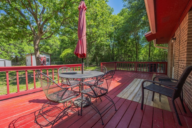205 Florence Dr, Defuniak Springs, FL 32433 - wooden deck with a storage unit, an outbuilding, outdoor dining area, and view of scattered trees