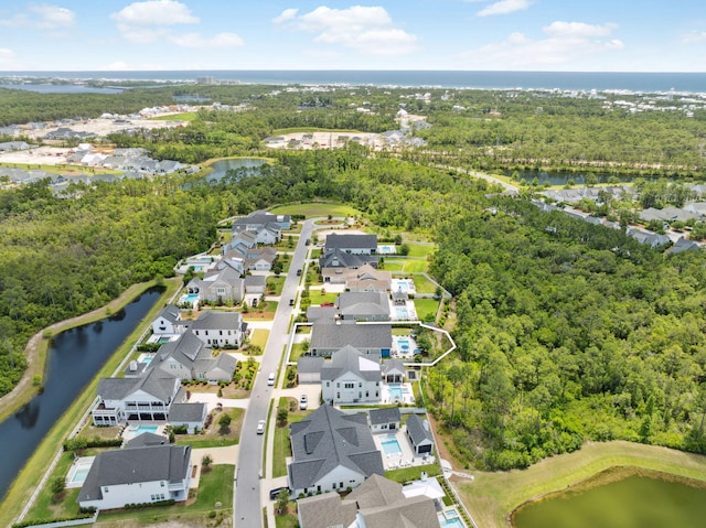 aerial view of residential area featuring a nearby body of water and a heavily wooded area