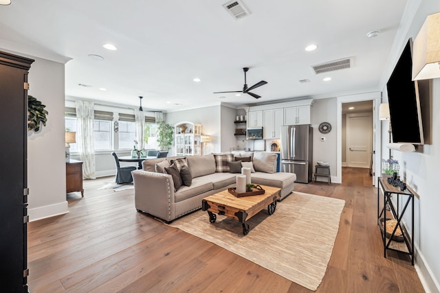 living room with hardwood / wood-style flooring, a ceiling fan, baseboards, ornamental molding, and recessed lighting