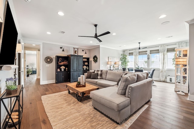 living room featuring a ceiling fan, baseboards, wood finished floors, recessed lighting, and crown molding