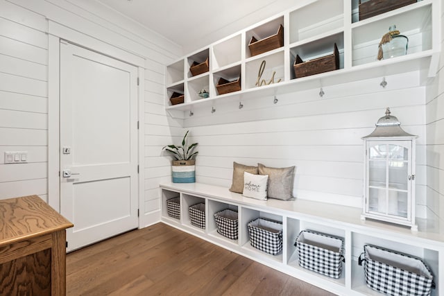 mudroom with dark wood-style floors and wooden walls