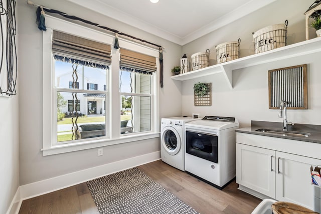 laundry room featuring separate washer and dryer, cabinet space, plenty of natural light, ornamental molding, and wood finished floors
