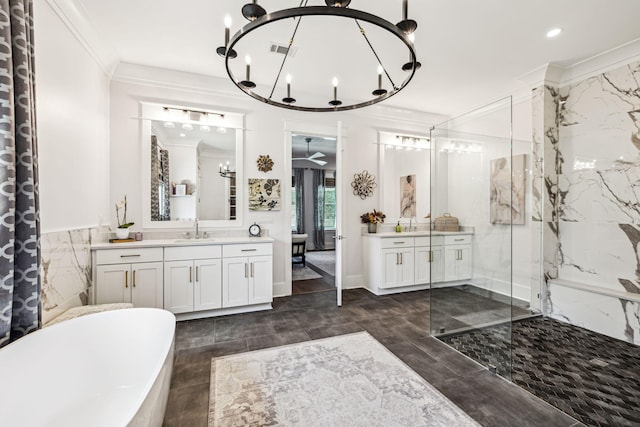 full bath featuring a chandelier, ornamental molding, a marble finish shower, a freestanding tub, and two vanities