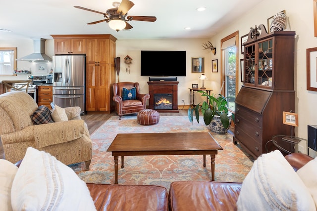 living room featuring light wood-style floors, ceiling fan, recessed lighting, and a glass covered fireplace