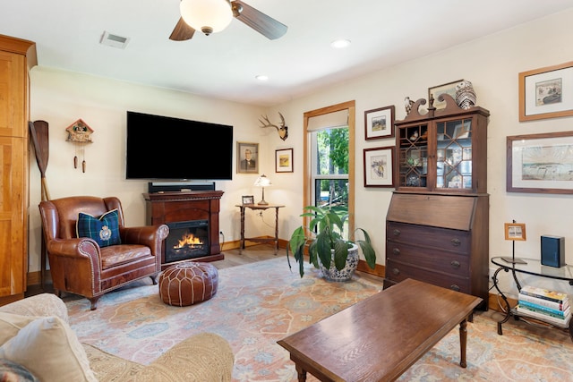 living room with baseboards, a glass covered fireplace, a ceiling fan, recessed lighting, and light wood-style flooring