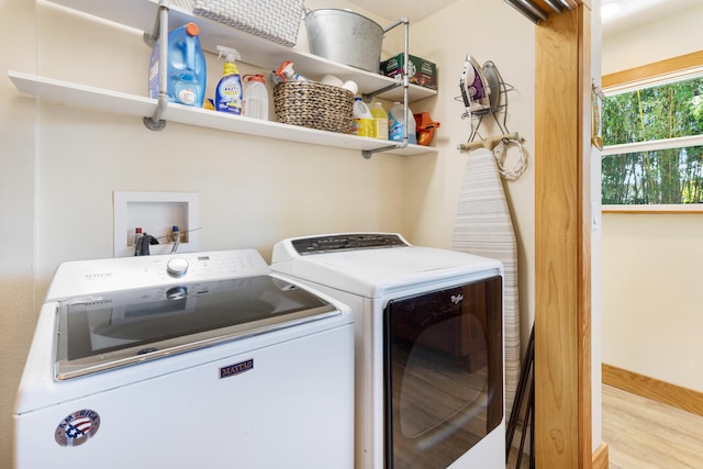 laundry room with washing machine and dryer, wood finished floors, and baseboards