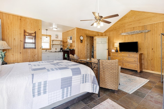 bedroom with wooden walls, stone tile flooring, lofted ceiling, a sink, and ceiling fan