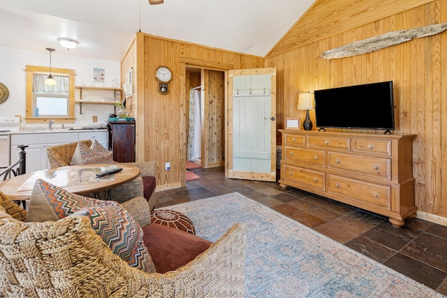 living area with wood walls, vaulted ceiling, stone tile flooring, and baseboards