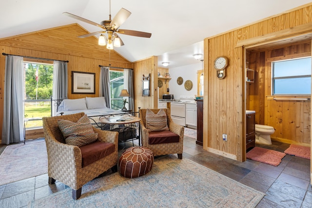 bedroom featuring wood walls, multiple windows, vaulted ceiling, stone tile flooring, and connected bathroom