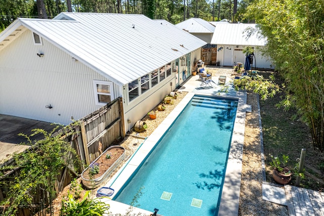 view of swimming pool featuring a patio area, a fenced backyard, and view of scattered trees