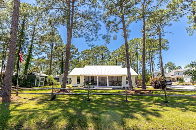 view of front of home featuring a sunroom, a front lawn, an outdoor structure, and a storage unit