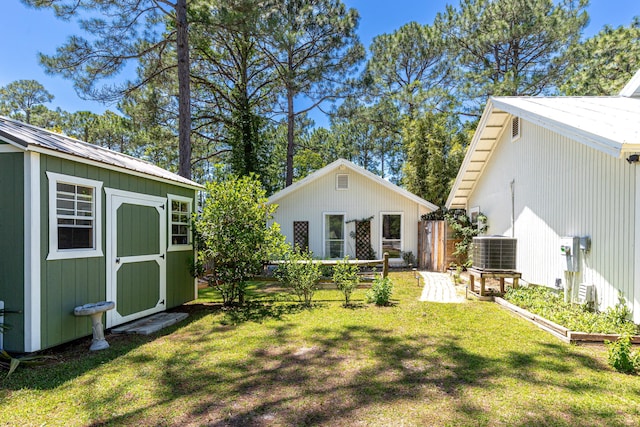 back of house featuring central AC, a lawn, an outdoor structure, and a shed