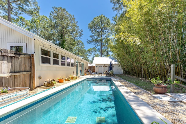 view of swimming pool with fence and an outdoor structure