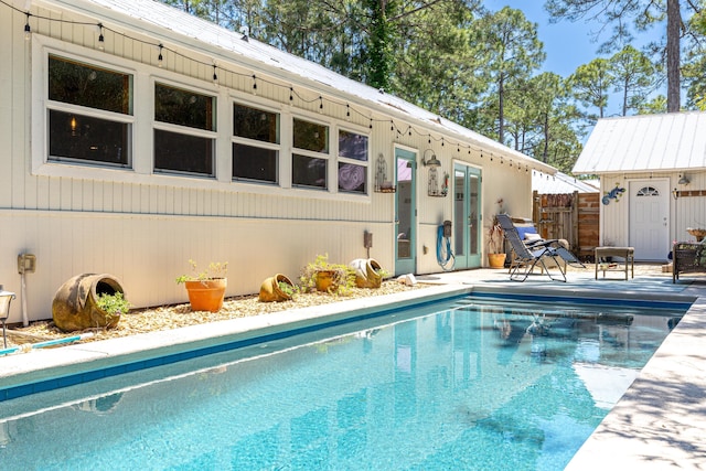 swimming pool with an outbuilding, fence, and a patio