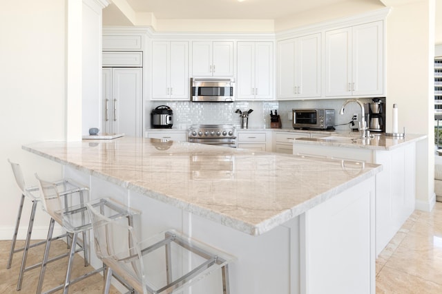 15400 Emerald Coast Pkwy Unit 301, Destin, FL 32541 - kitchen featuring appliances with stainless steel finishes, white cabinetry, backsplash, and light stone countertops