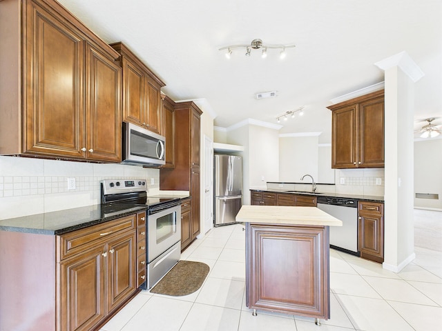 5261 Moore Loop, Crestview, FL 32536 - kitchen with stainless steel appliances, decorative backsplash, light tile patterned flooring, a center island, and ornamental molding