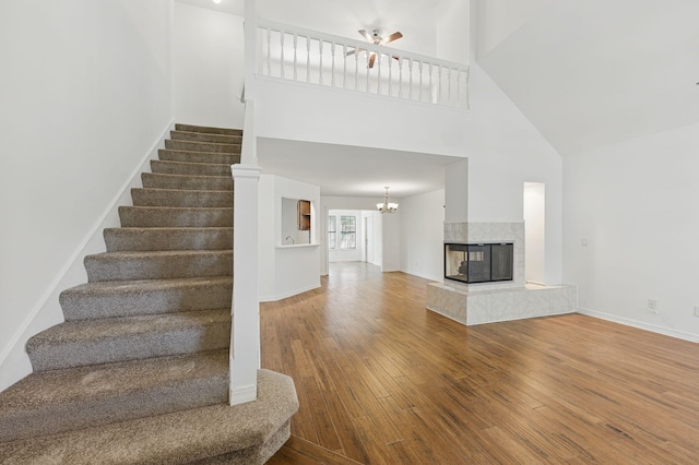 1405 Ariel Ln, Fort Walton Beach, FL 32547 - staircase featuring a towering ceiling, hardwood / wood-style floors, a ceiling fan, a chandelier, and baseboards