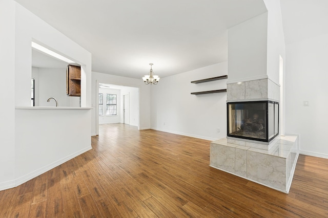 1405 Ariel Ln, Fort Walton Beach, FL 32547 - unfurnished living room featuring a chandelier, a tiled fireplace, wood finished floors, and baseboards