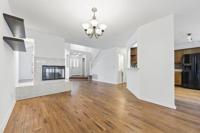1405 Ariel Ln, Fort Walton Beach, FL 32547 - unfurnished living room featuring wood finished floors, a chandelier, baseboards, and a tiled fireplace