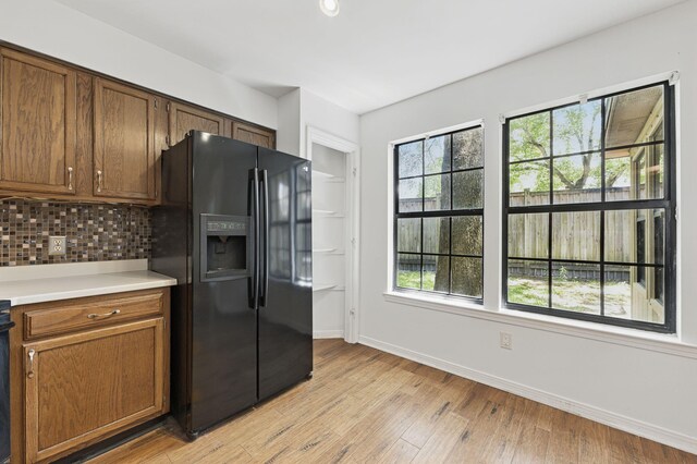 1405 Ariel Ln, Fort Walton Beach, FL 32547 - kitchen with black refrigerator with ice dispenser, tasteful backsplash, baseboards, light countertops, and light wood-style flooring
